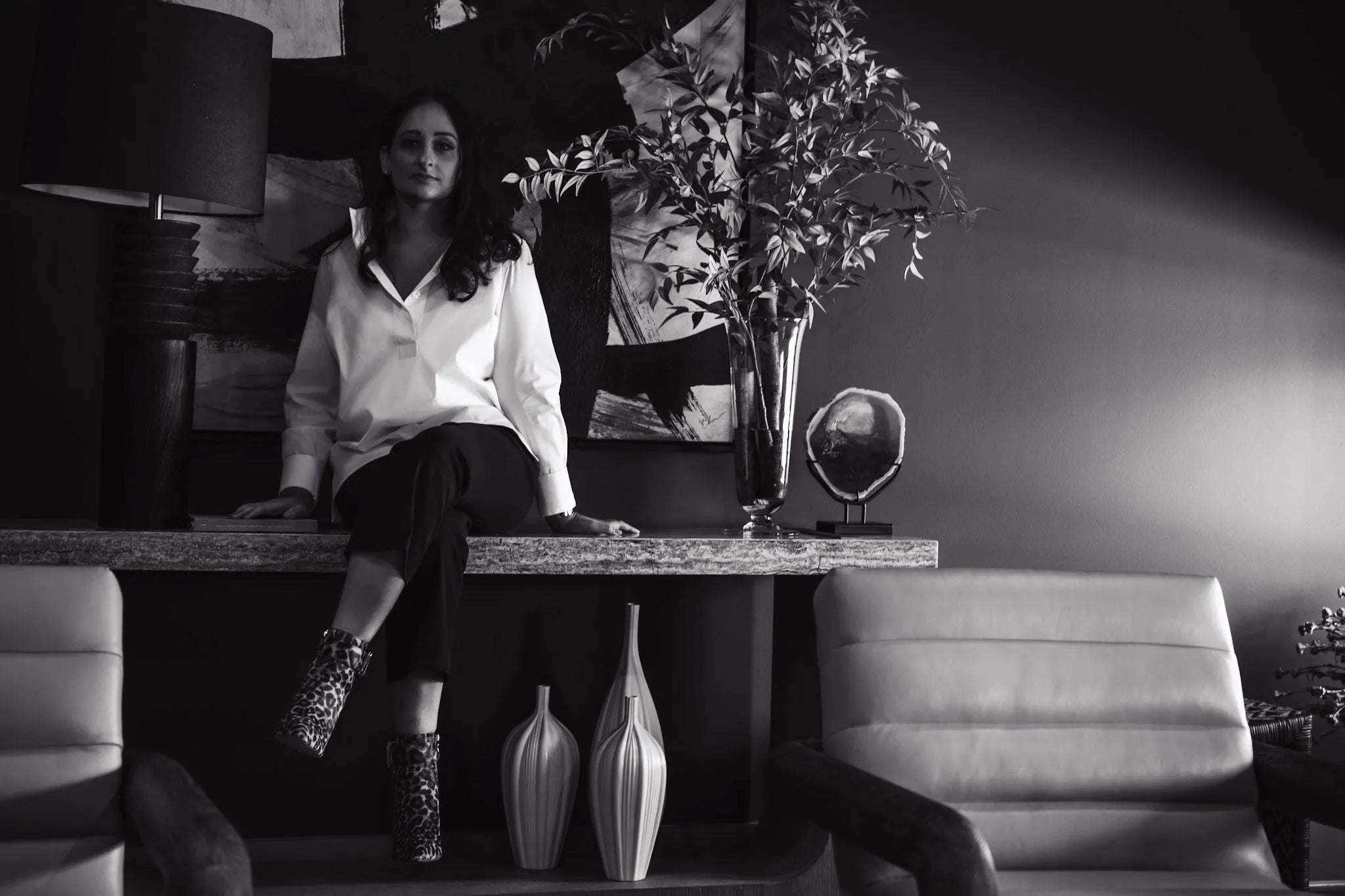 Woman sitting on a table in a stylish room with decor elements.