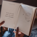Open book held by a person with text and illustration on the pages