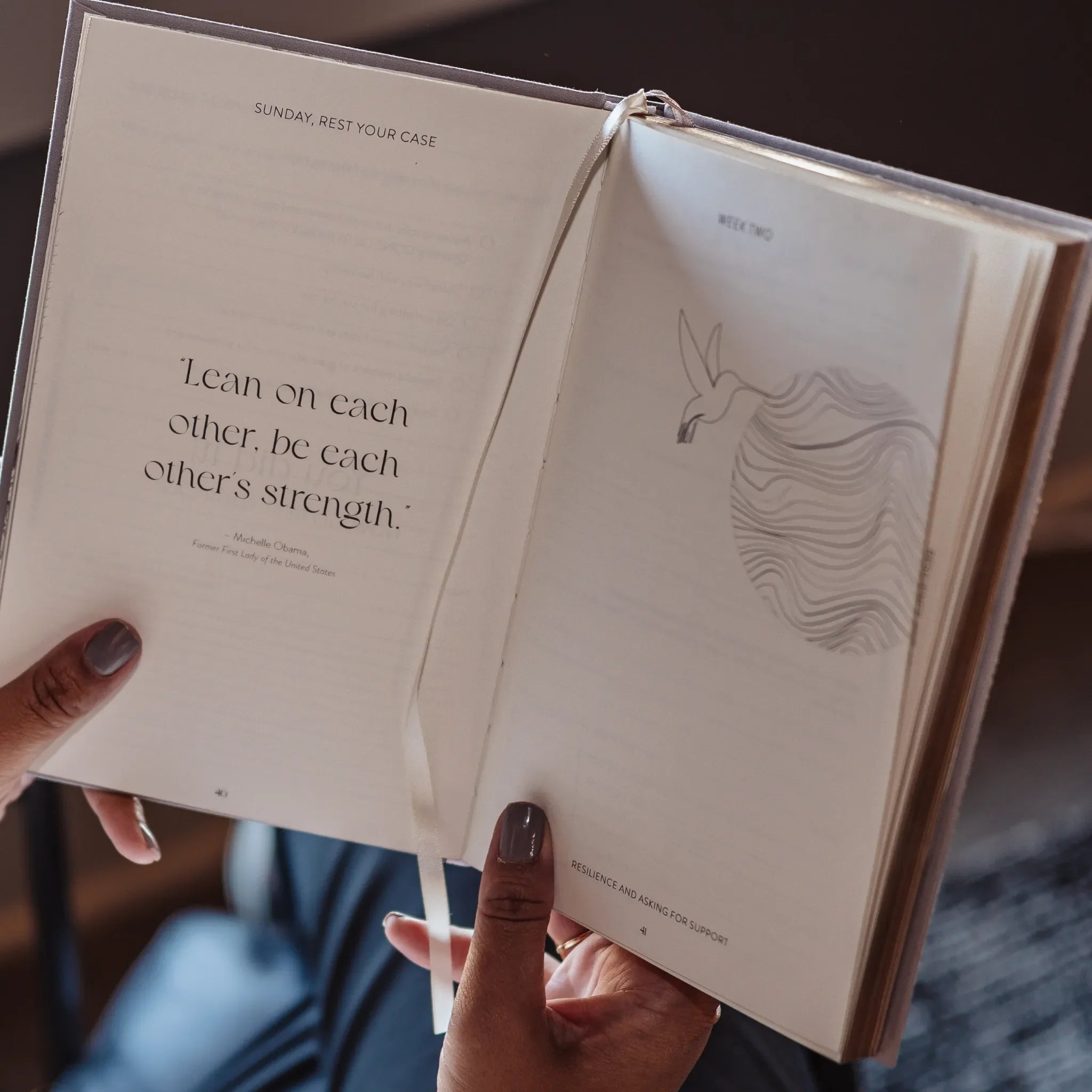 Open book held by a person with text and illustration on the pages