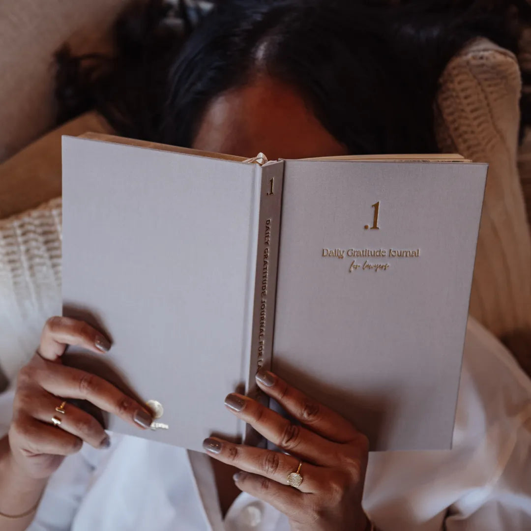 Person holding a beige journal titled '.1 Daily Gratitude Journal for Lawyers'.
