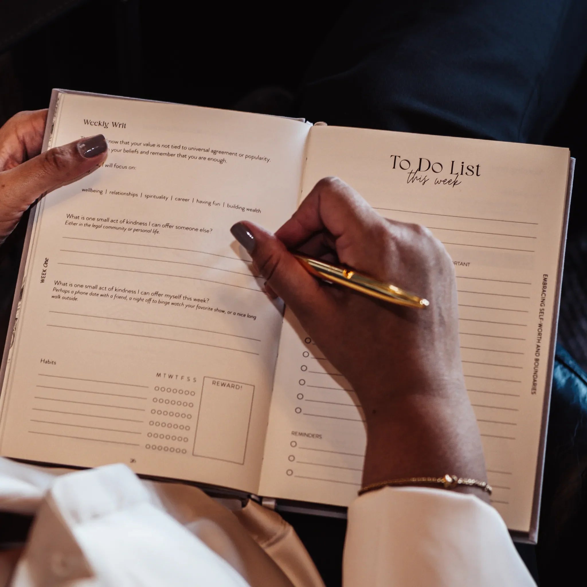 Person holding a planner with a 'To Do List' and 'Weekly Wrap' sections, using a pen.