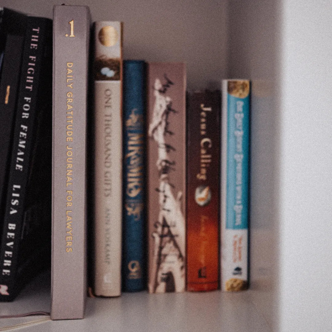 Row of books on a shelf with visible spines. On titled '.1 Daily Gratitude Journal for Lawyers'.