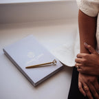 Notebook with a logo of Clairty Print Co and a person's arm on a light surface