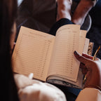 Person holding a planner with a pen, sitting on a couch.