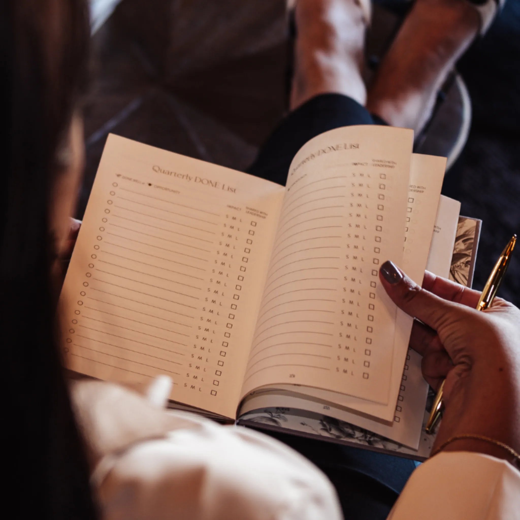 Person holding a planner with a pen, sitting on a couch.