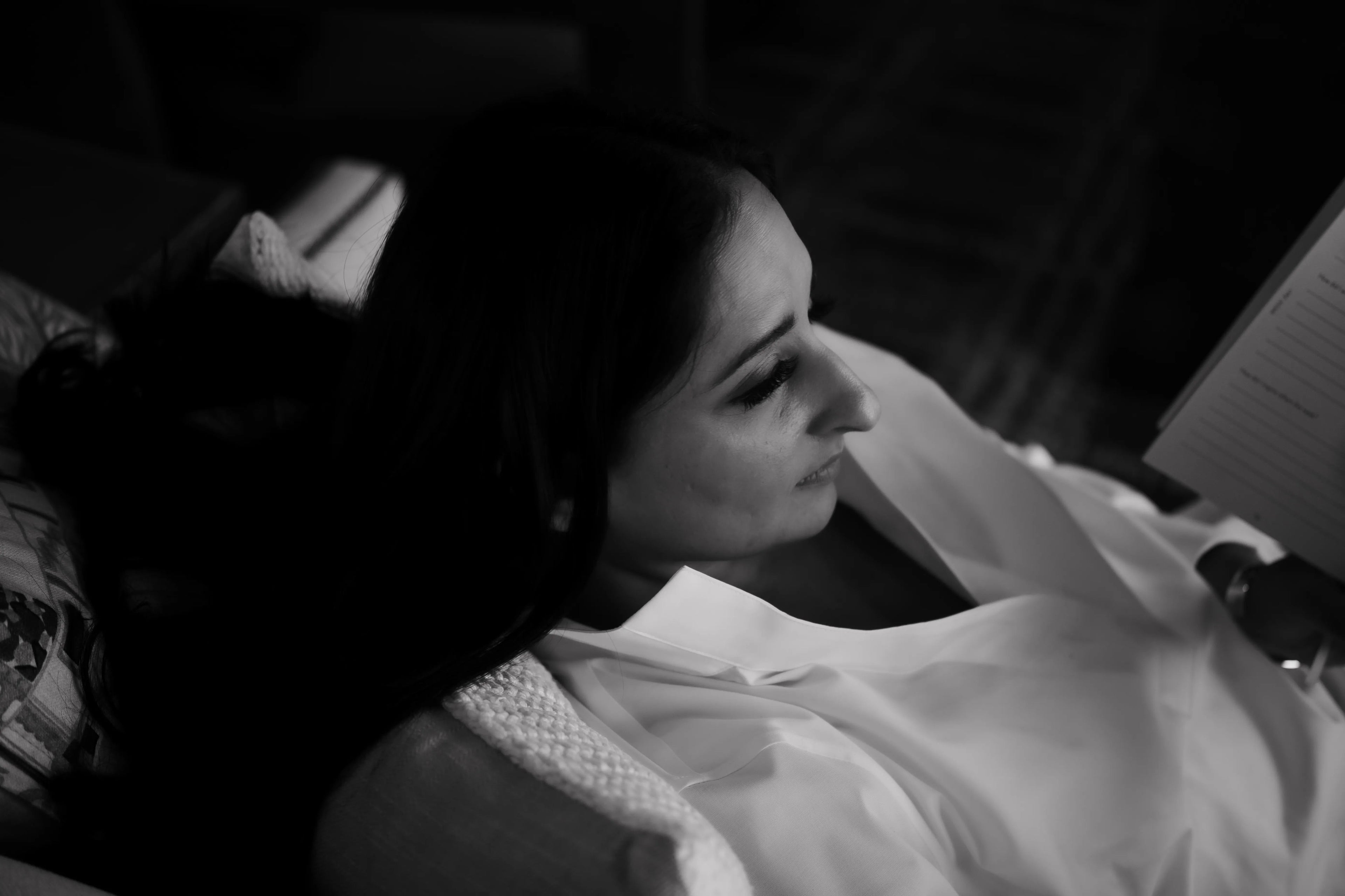 Black and white photo of a person lying in bed with a blanket looking at the .1 daily gratitude journal for lawyers