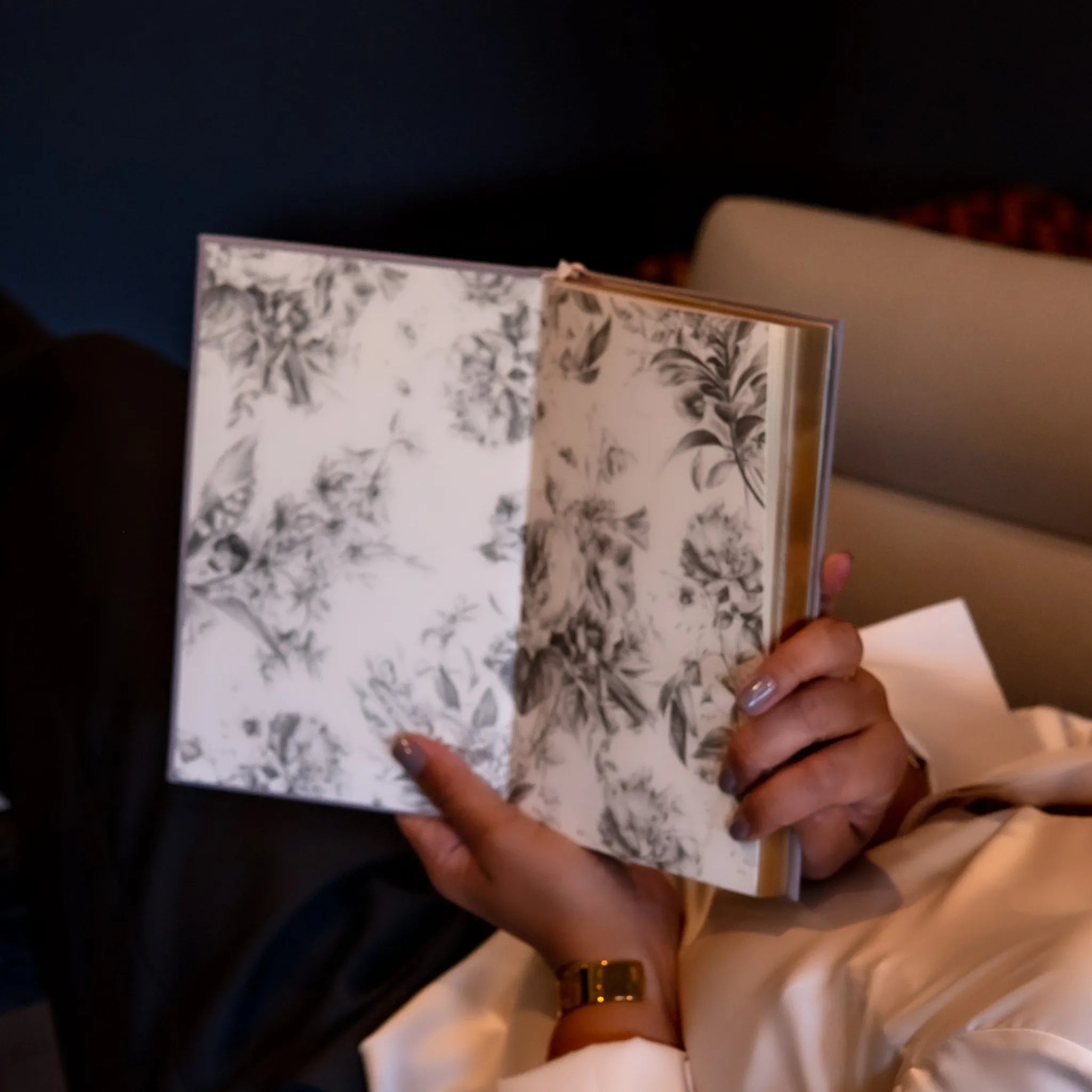 Hand holding a floral-patterned notebook against a dark background