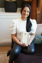 Woman sitting on a couch holding a book in a living room setting