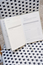 Open planner on a woven chair with a checkered pattern
