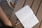 Open book on a wooden surface with a blurred person and basket in the background